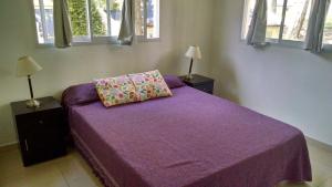 1 dormitorio con 1 cama de color púrpura con 2 lámparas y ventanas en mi encanto, en Mar Azul