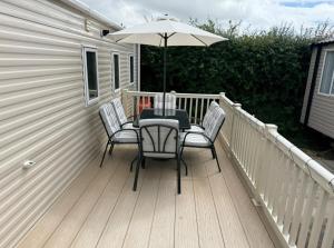 a table and chairs on a deck with an umbrella at Ty hedd static caravan in Caernarfon