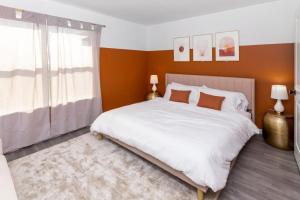 a bedroom with a large white bed with orange walls at Newly Renovated l Fire Pit Hot Tub Arcade in Indianapolis