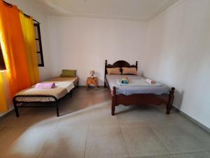 タラファルにあるBarros Homestayのベッド2台と椅子が置かれた部屋