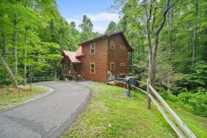 a log cabin in the woods next to a road at Poolin Around by American Patriot Getaways in Glade
