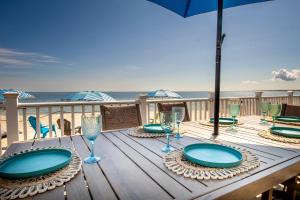 a wooden table with plates and wine glasses on the beach at Oceanfront Cape Cod House by Rock Properties in Sandwich