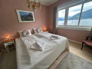 a bedroom with a white bed with a large window at Sognefjord Gjesteheim in Vangsnes