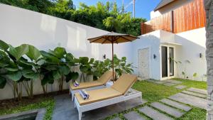 a patio with two chairs and an umbrella at Villa Nak Anak Sanur - Private Luxury 2BR Villa with Pool in Sanur