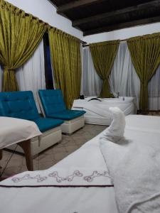 a hotel room with two beds and blue chairs at Hotel Rural Granja Agroecoturistica Santa Barbara in Simijaca