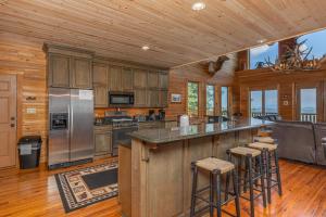 a kitchen with wooden cabinets and a island with bar stools at Sky View by American Patriot Getaways in Park Settlement