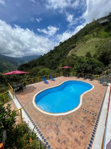a pool with chairs and umbrellas next to a mountain at Paraiso brisas de la naturaleza in Tona