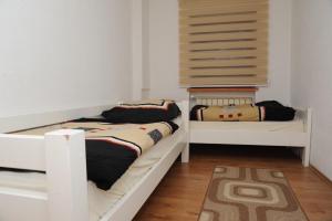 two beds in a room with white walls and wooden floors at Ice Queen Vlasic in Šišava
