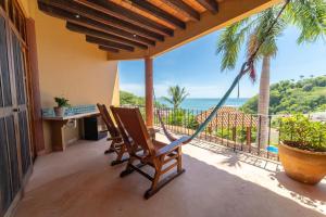 a porch with two chairs and a hammock overlooking the ocean at Casa Ceiba Huatulco - Adults Only in Santa Cruz Huatulco
