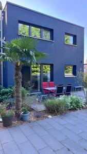 a house with chairs and a palm tree in front of it at FeWo im Vest in Oer-Erkenschwick