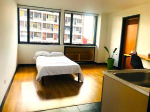 a room with a bed and two windows and a sink at Habitaciones junto a Clinica Marly in Bogotá