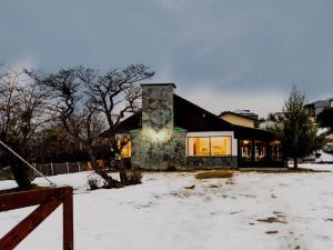 una casa con una chimenea de piedra en la nieve en CASA WAIA ULU, en Ushuaia