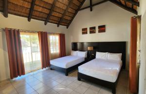a bedroom with two beds and a window at Shumba Valley Lodge Lanseria Airport in Lanseria +63 photos