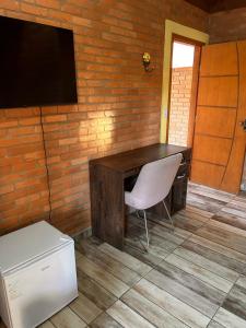 un bureau avec une chaise et une télévision sur un mur de briques dans l'établissement Casa Girassol, à Conceição da Ibitipoca