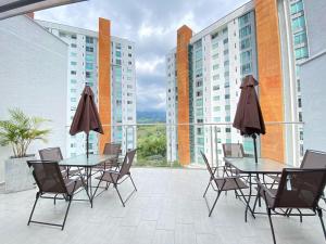 a patio with tables and chairs and a view of buildings at Belmonte 316-Apartamento luxury con pisicina en Av centenario in Armenia