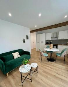 a living room with a green couch and a table at Quiet apartment - Touraine in Sorigny
