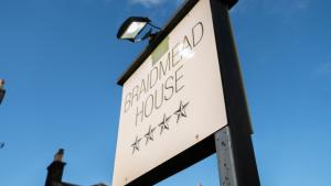 a sign for a bus stop with the sky in the background at Braidmead House in Irvine