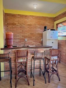 une cuisine avec un bar avec trois chaises et un réfrigérateur dans l'établissement Casa Girassol, à Conceição da Ibitipoca