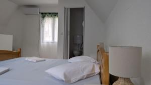a bedroom with a bed with white sheets and a lamp at River`s Song Cottage Jajce in Jajce