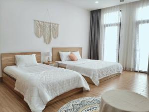 a bedroom with two beds with white sheets at Là lá 1 Vinhome Grand Park in Gò Công