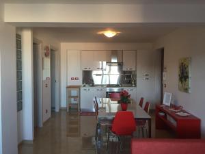 a kitchen and dining room with a table and red chairs at Baia Giardini Apartments in Giardini Naxos