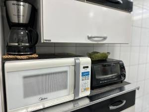 a microwave sitting on a shelf next to a blender at Apto 1 dorm no Canto do Forte - Próximo a Praia! in Praia Grande +47 photos