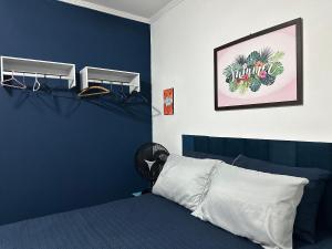 a bedroom with a bed with a blue wall at Apto 1 dorm no Canto do Forte - Próximo a Praia! in Praia Grande