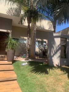a house with palm trees in front of a yard at Casa de alto padrão, 2 minutos do shopping in Tangara da Serra