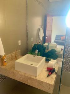 a bathroom with a white sink and a mirror at Casa de alto padrão, 2 minutos do shopping in Tangara da Serra