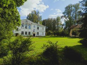 a large white house on a grassy field at Bērzgala Viesu Nams  +15 photos