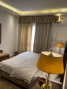 a bedroom with a bed with a lamp and a window at Luxury Apartment in Cairo, October, Sheikh Zayed in 6th Of October +24 photos