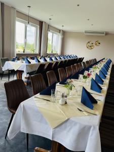 a row of tables in a room with blue napkins at Hotel Trebeltal in Demmin