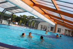 a group of people swimming in a swimming pool at Sfeervolle woodlodge op 5 sterren vakantiepark in Raalte