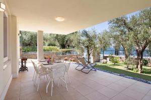 een terras met een tafel, stoelen en bomen bij Apartment Righini in Torri del Benaco