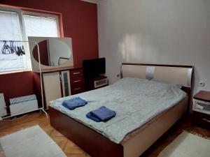 a bedroom with a bed with two blue towels on it at Apartment "Daisy Flower" - Center, Bitola in Bitola