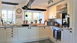 une cuisine avec des armoires blanches et une horloge au mur dans l'établissement The Old Farmhouse, Yealand Redmayne, near Carnforth, à Beetham 18 autres photos
