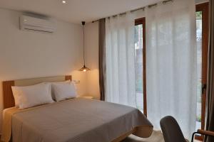 ein Schlafzimmer mit einem Bett und einem großen Fenster in der Unterkunft Refúgio da Ribeira in São Vicente