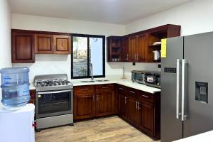 a kitchen with wooden cabinets and stainless steel appliances at Hotel Termales La Montaña in Ahuachapán