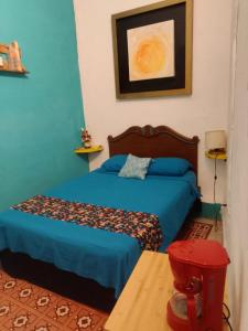 a bedroom with two beds with blue walls and a table at La Casa del Kéej Hostel in Mérida +45 photos