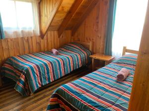 a bedroom with two beds in a wooden cabin at Cabañas Santa María in Pichilemu