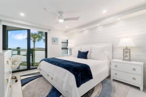 a white bedroom with a large bed and a window at Riverside Club A209 in Marco Island