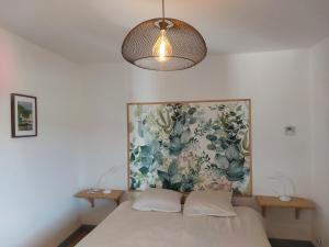 a bedroom with a bed with a painting on the wall at Gite du Château le Mas in Saint-Laurent-des-Hommes