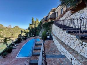 マッゼオにあるVilla Incanto di Mareの建物の隣の石垣の隣にあるプール