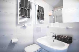 a white bathroom with a sink and a toilet at HAUS Lampacher in Ganda di Martello
