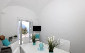Una sala de estar blanca con una mesa y sillas. en Villa Dei in Positano - Camere, en Positano