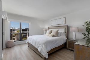 a white bedroom with a large bed and a window at Sundial F403 - Beach Bliss in Sanibel +8 photos