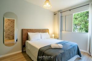 a bedroom with a bed and a large window at Apto Central a 600m da Beira-Mar Norte SGS0106 in Florianópolis