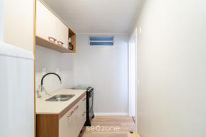 a small kitchen with a sink and a mirror at Apto Central a 600m da Beira-Mar Norte SGS0106 in Florianópolis +5 photos