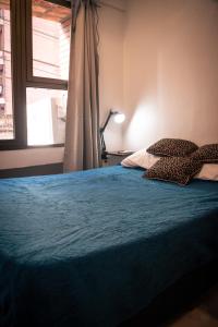 ein Schlafzimmer mit einem Bett mit blauen Laken und einem Fenster in der Unterkunft Numá Lior Departamentos - Casco Histórico in San Miguel de Tucumán