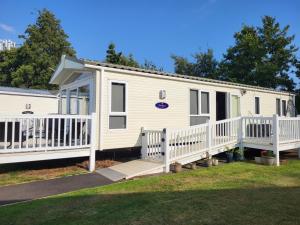 a mobile home with a porch and a deck at Elegant 2 Bedroom En-Suite Caravan with Bathtub near Edinburgh Seton Sands Holiday Village in Port Seton